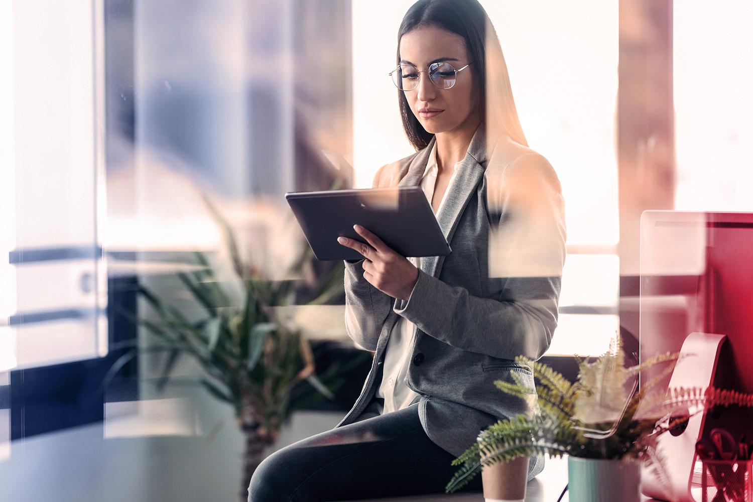 Frau steht im Büro mit Tablet