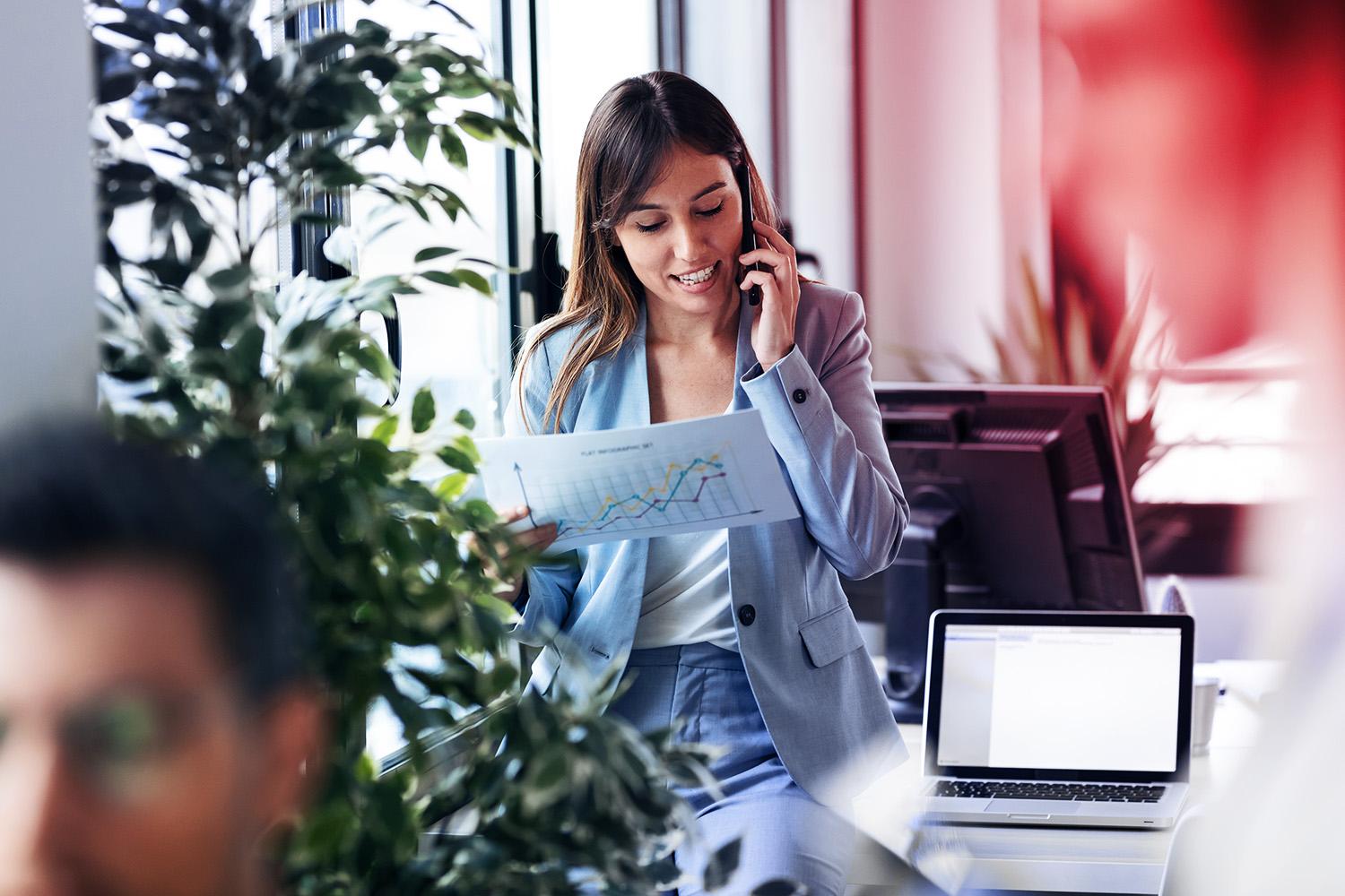 Frau steht im Büro und telefoniert