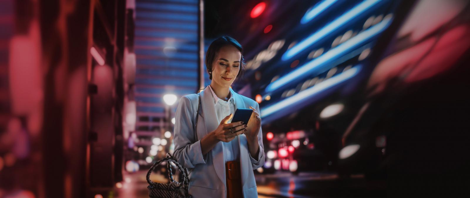 Frau steht in der Stadt mit Smartphone