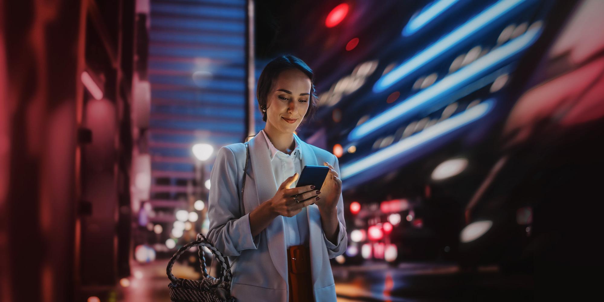 Frau steht in der Stadt mit Smartphone